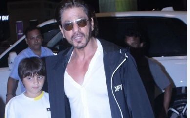 As they walk to the airport, Shah Rukh Khan holds his son AbRam's hand.